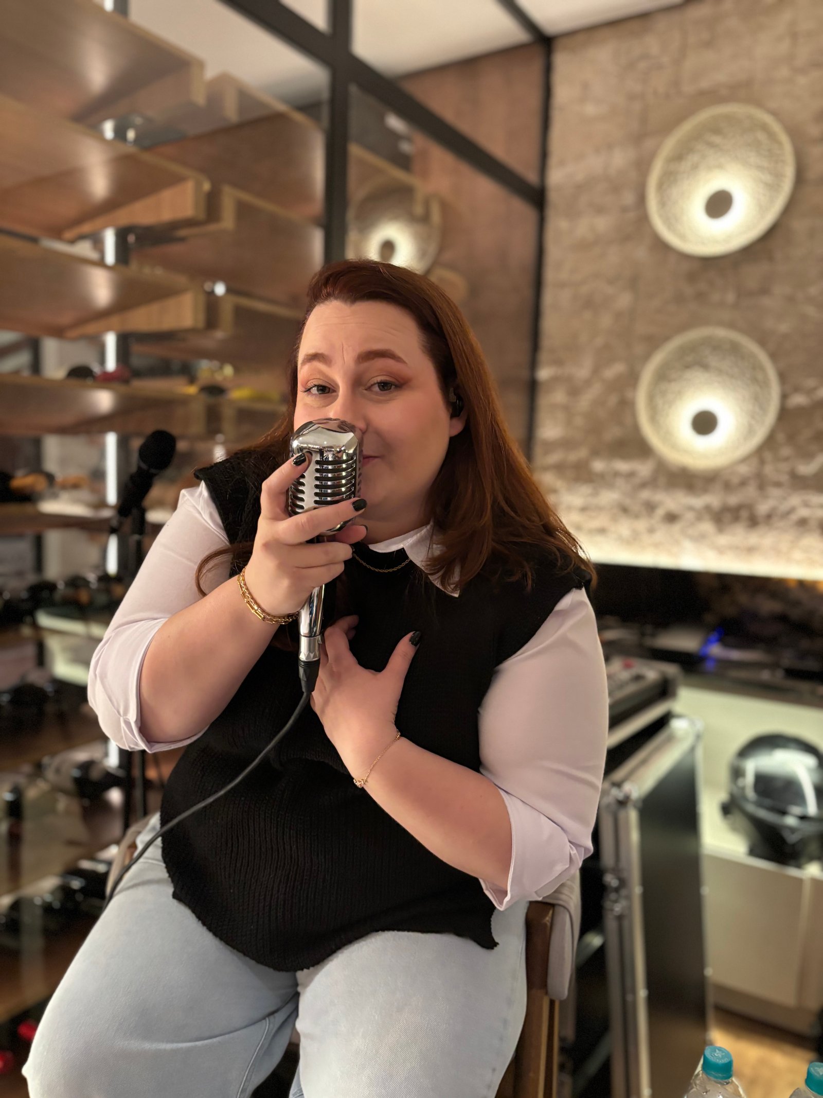 Jaque cantando com um microfone vintage, olhando para a câmera